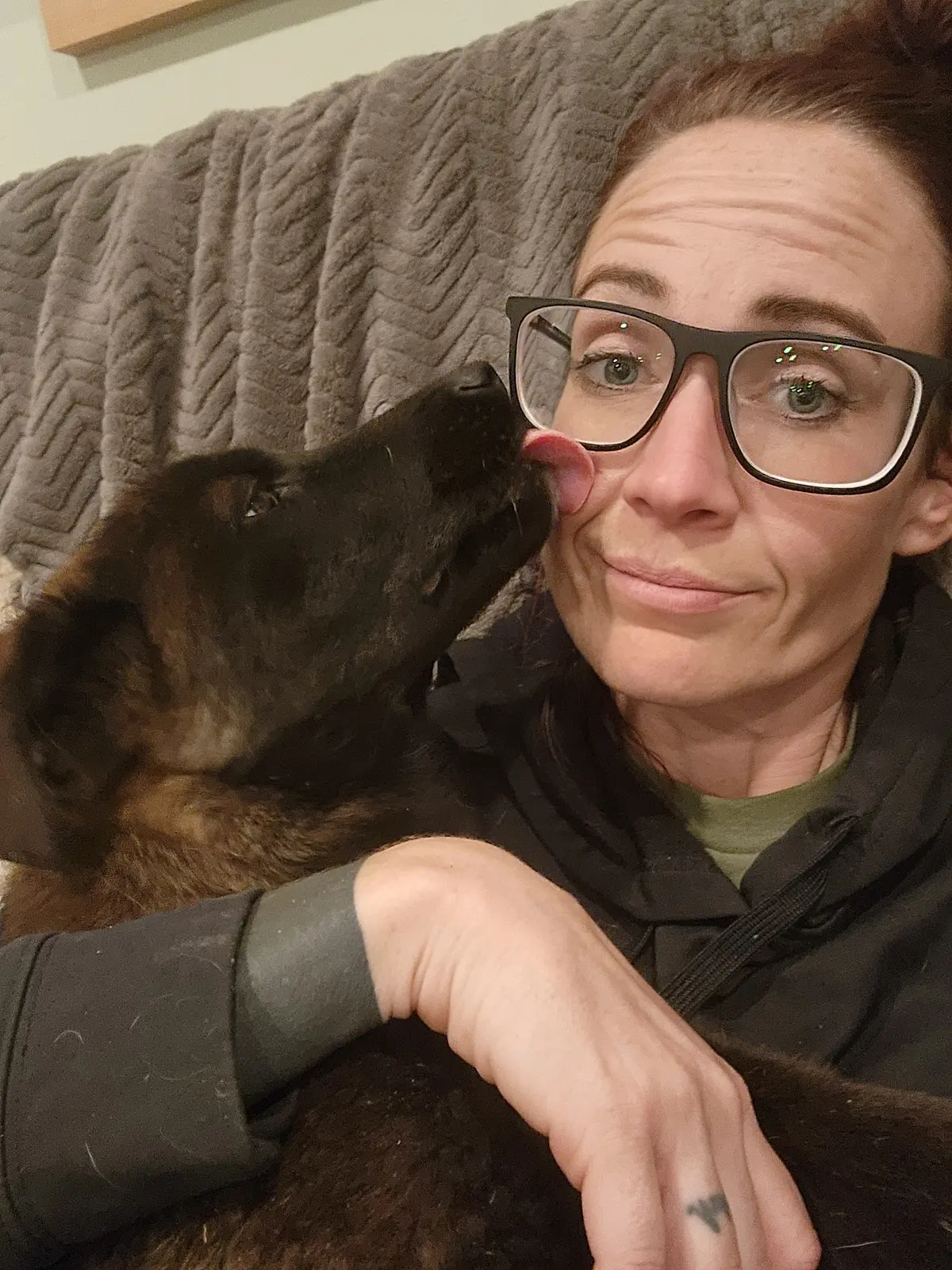 A foster caregiver receiving a kiss from a puppy